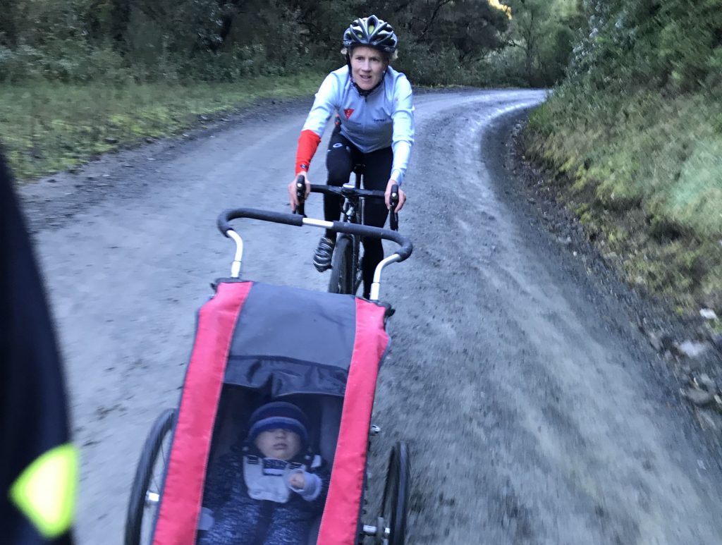 Britta Martin bicycling with baby Jordy in pushpram.