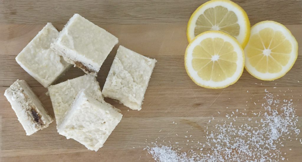 raw lemon slice on a chopping board with lemons and sprinkled dissicated coconut